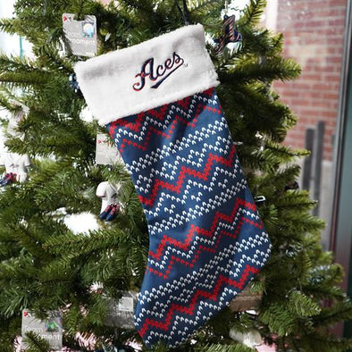 Christmas stocking with zigzag pattern and 'Aces' text on a decorated tree.